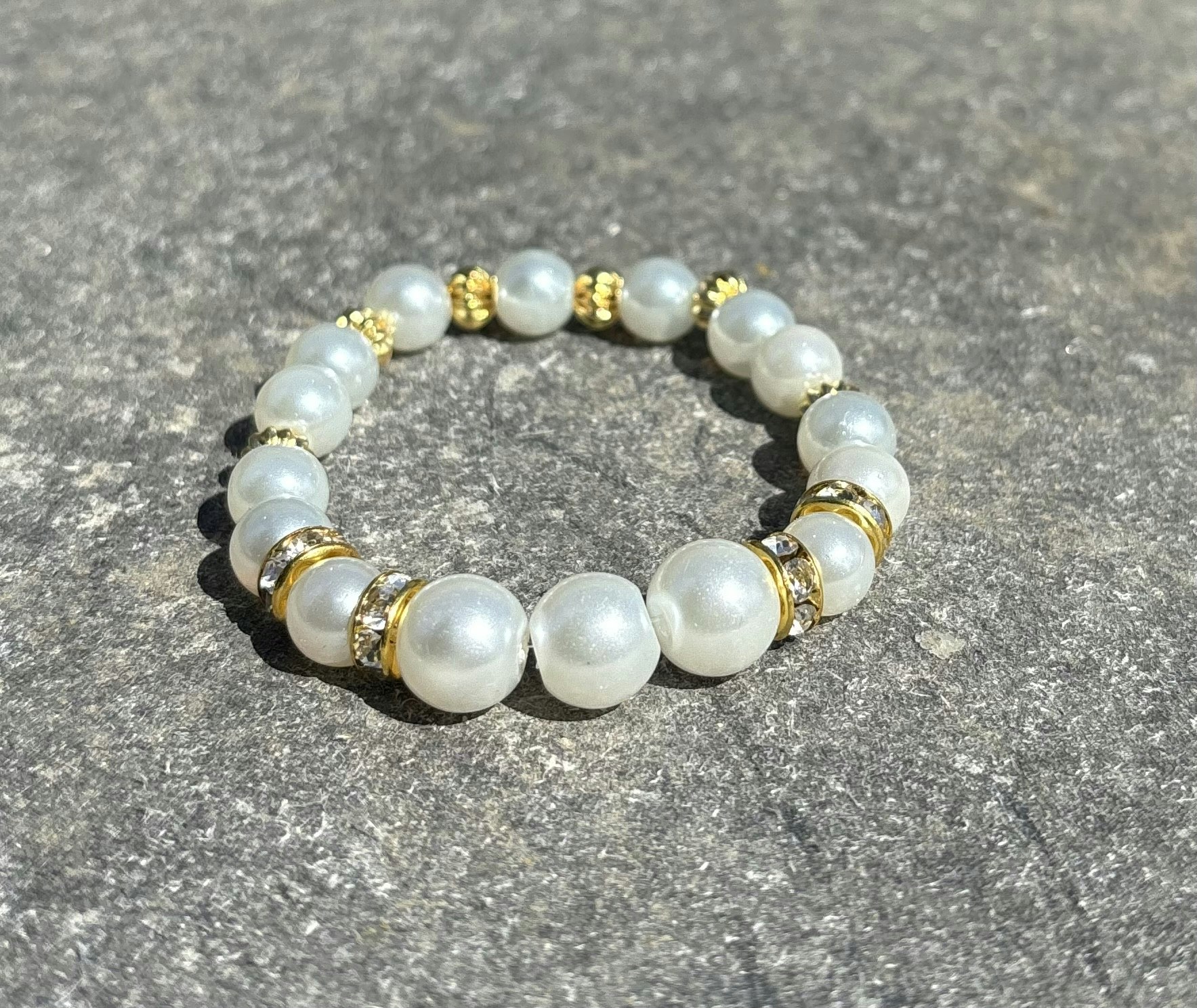 Armband med vita glaskulor och guldiga detaljer