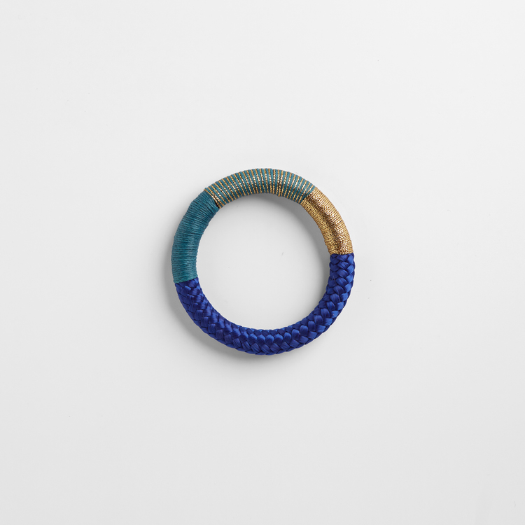 Armband av blått rep. Partier av repet är virat med guldlurex och turkos bomullstråd.