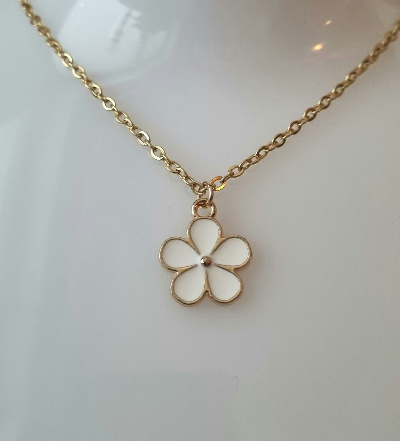 Guldfärgat halsband med en vit blomma, blomberlock / charm