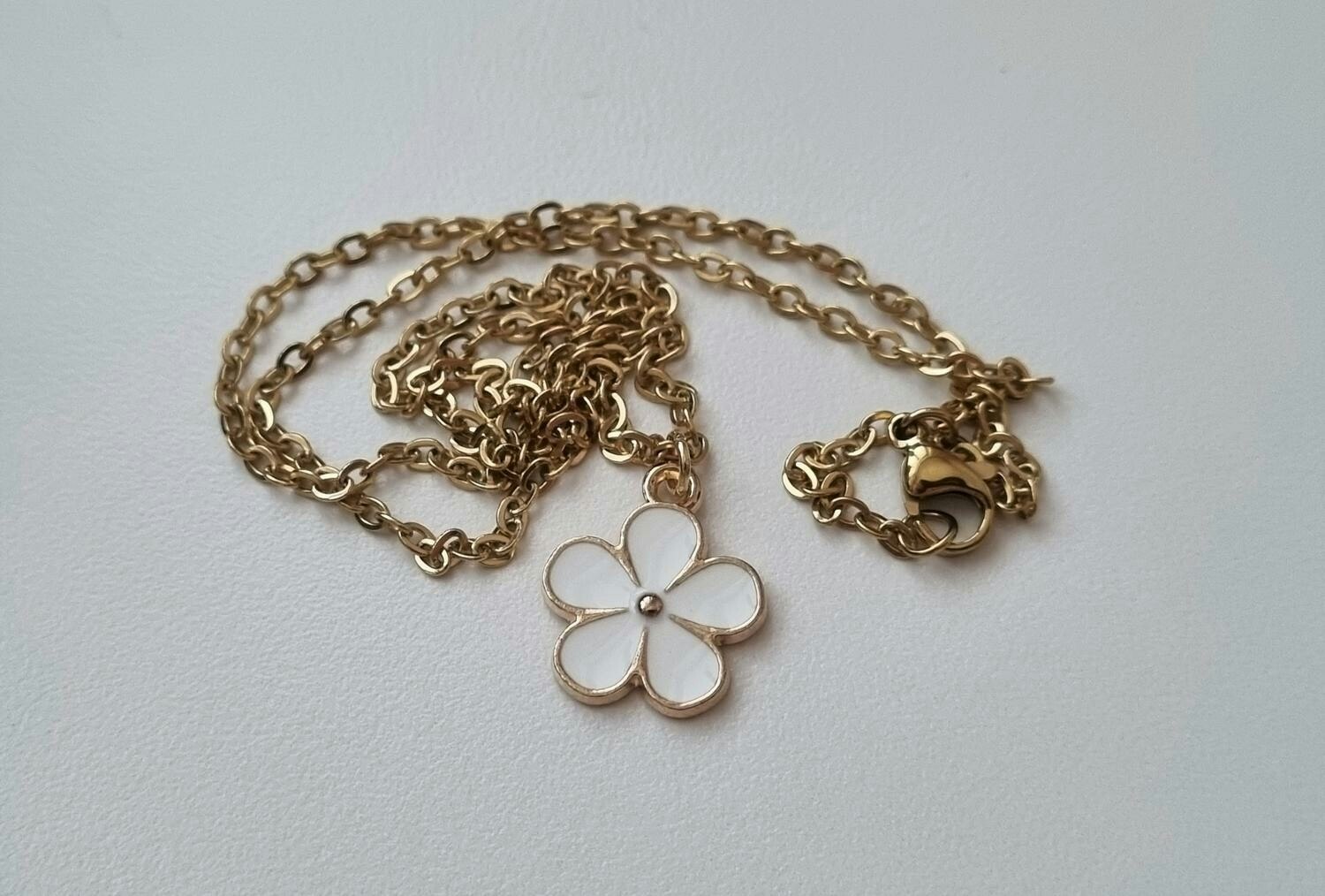 Guldfärgat halsband med en vit blomma, blomberlock / charm