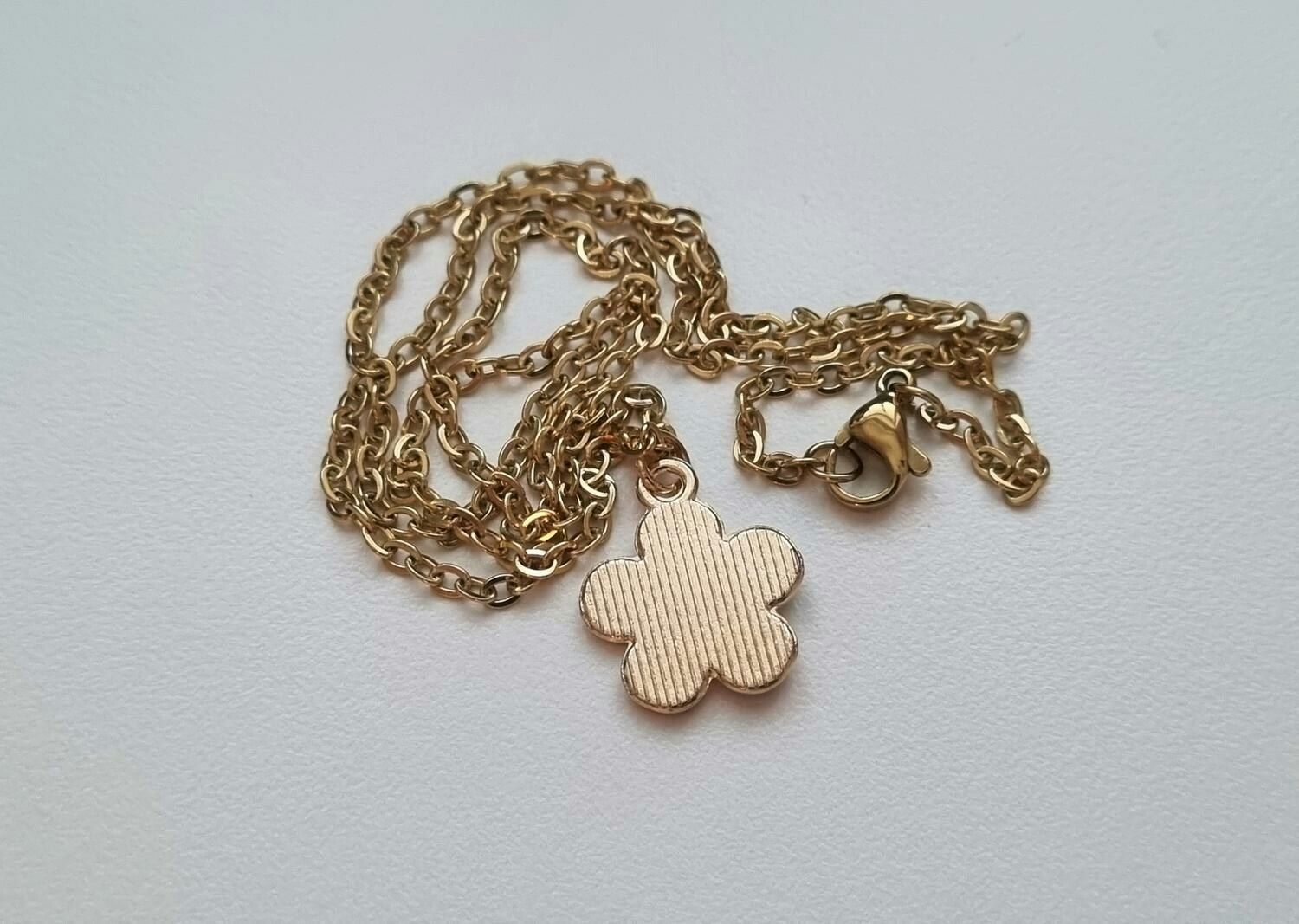 Guldfärgat halsband med en vit blomma, blomberlock / charm