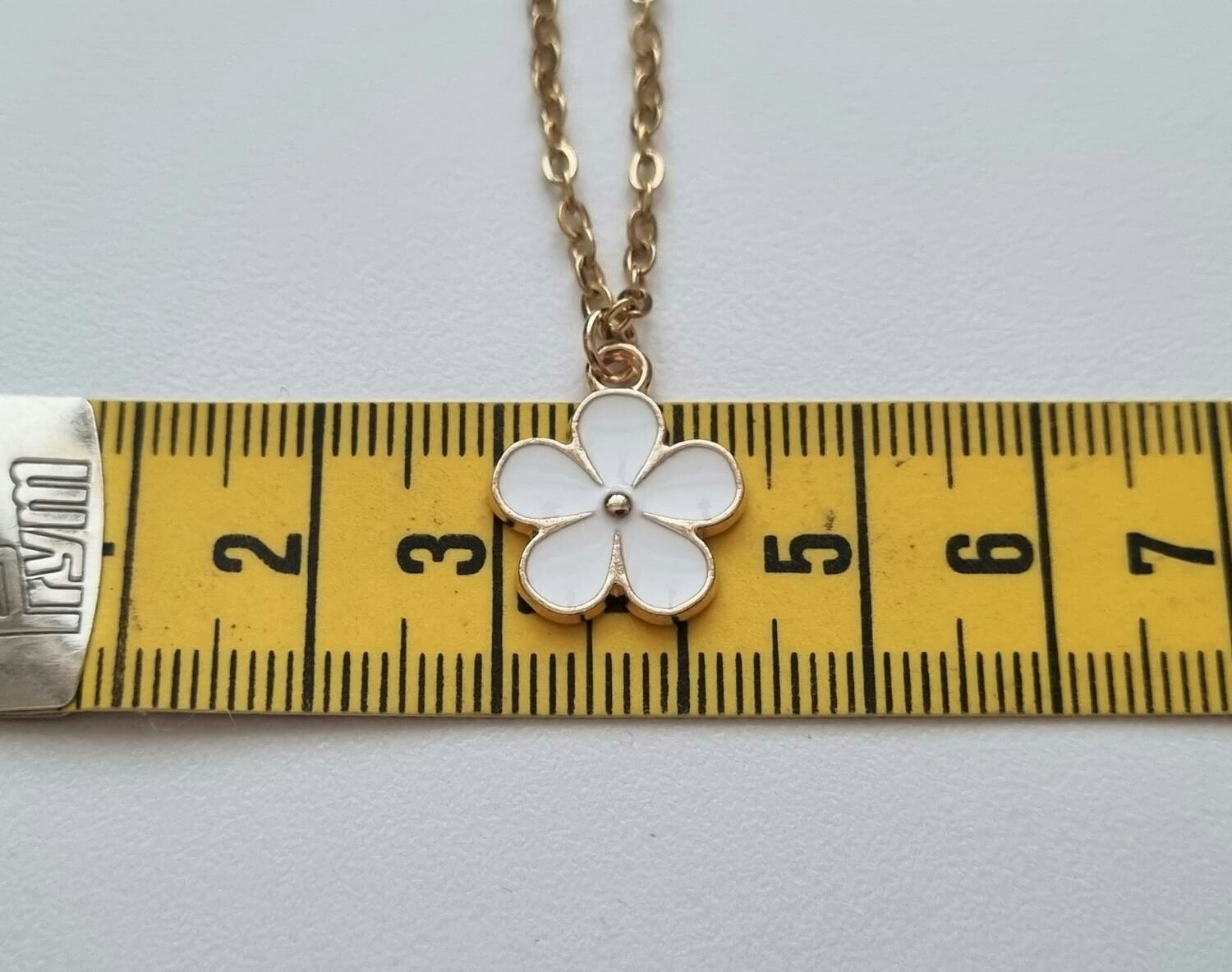 Guldfärgat halsband med en vit blomma, blomberlock / charm