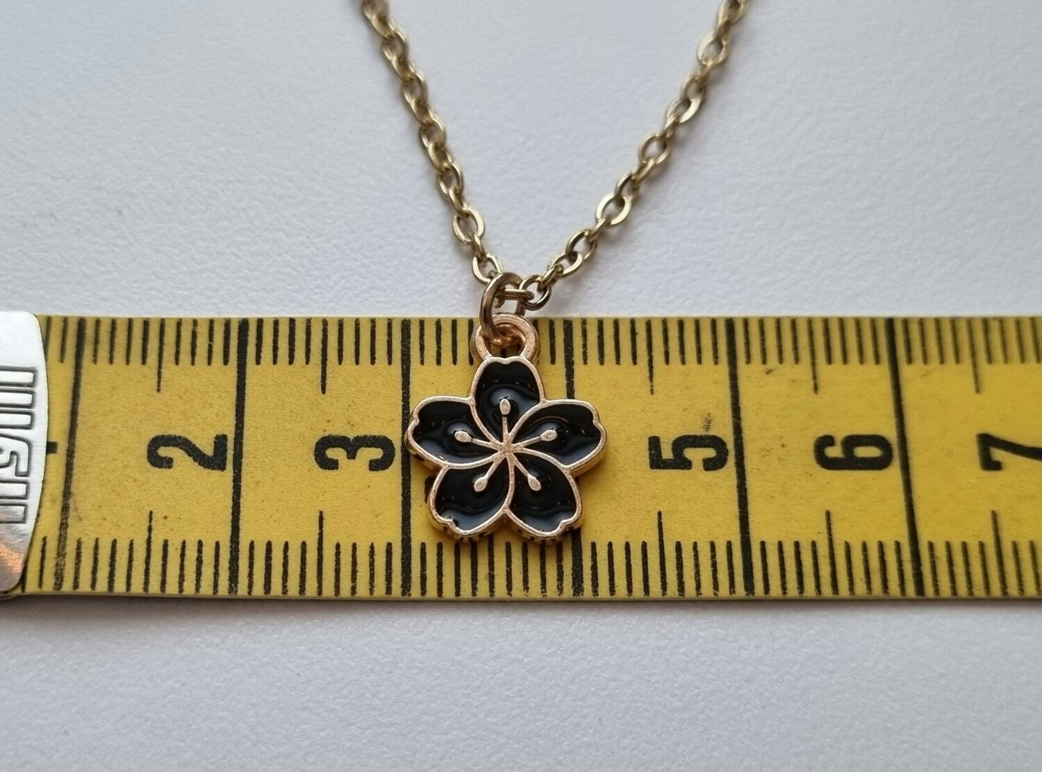 Guldfärgat halsband med en svart blomma