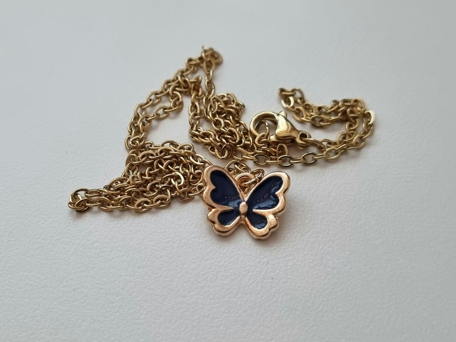 Guldfärgat halsband med en svart fjäril / fjärilsberlock