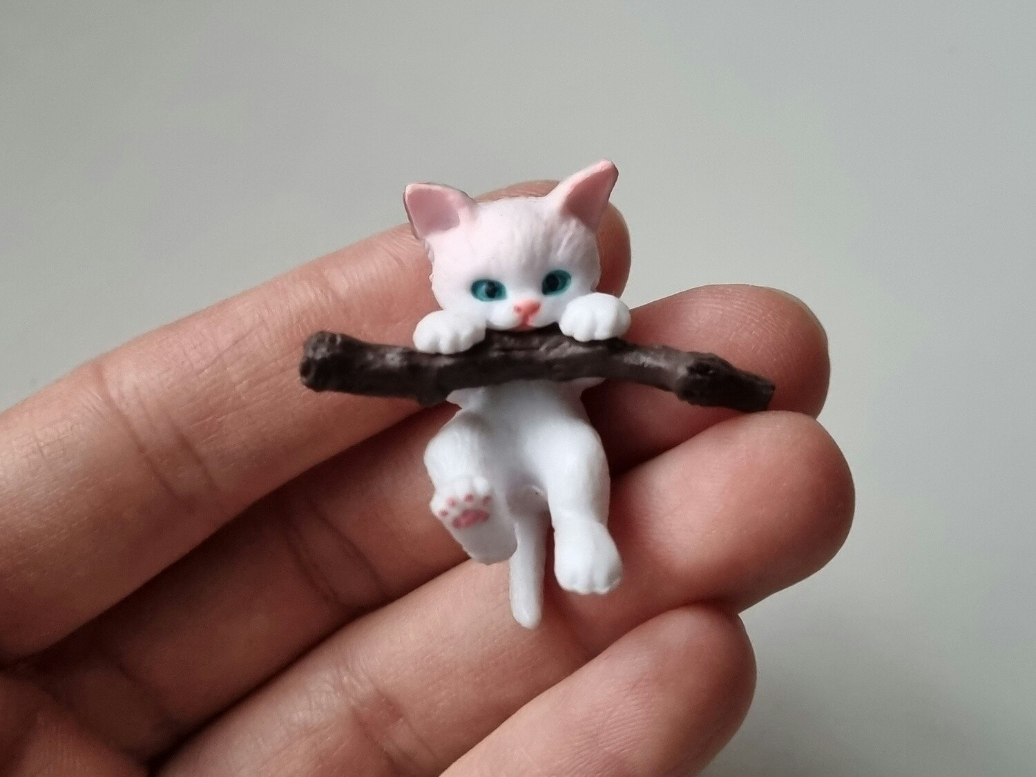Gullig katt som klamrar sig fast vid en gren / miniatyr
