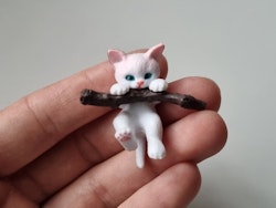 Gullig katt som klamrar sig fast vid en gren / miniatyr