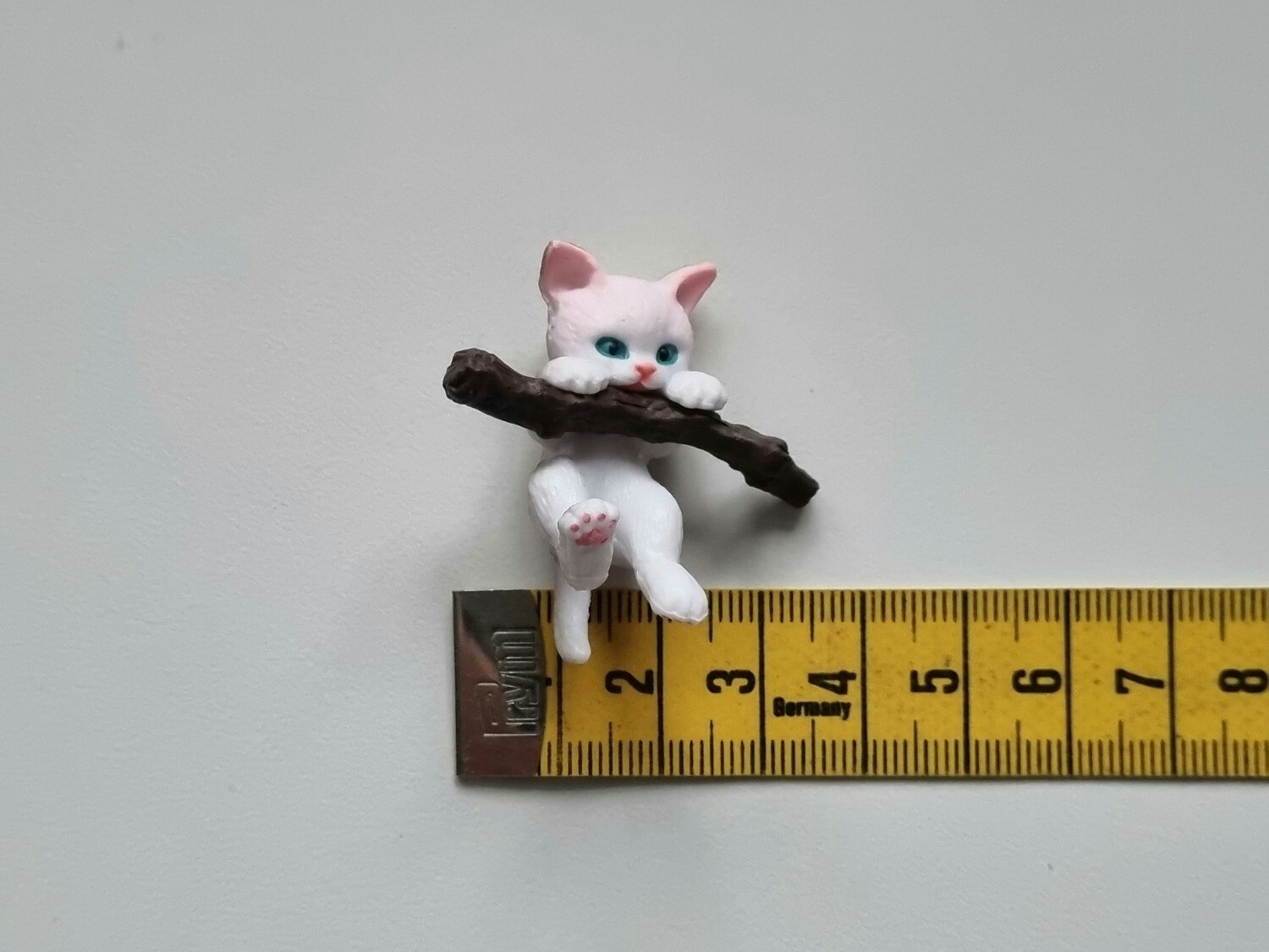 Gullig katt som klamrar sig fast vid en gren / miniatyr