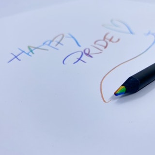 Svart penna som skriver i regnbågsfärger