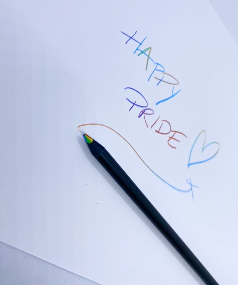 Svart penna som skriver i regnbågsfärger