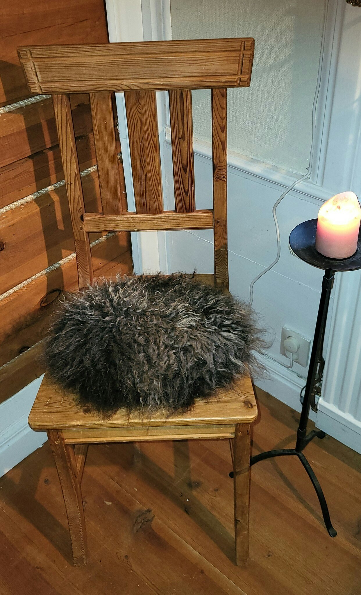 Stolsdyna av fårskinn, svart med silvergrå lockar.