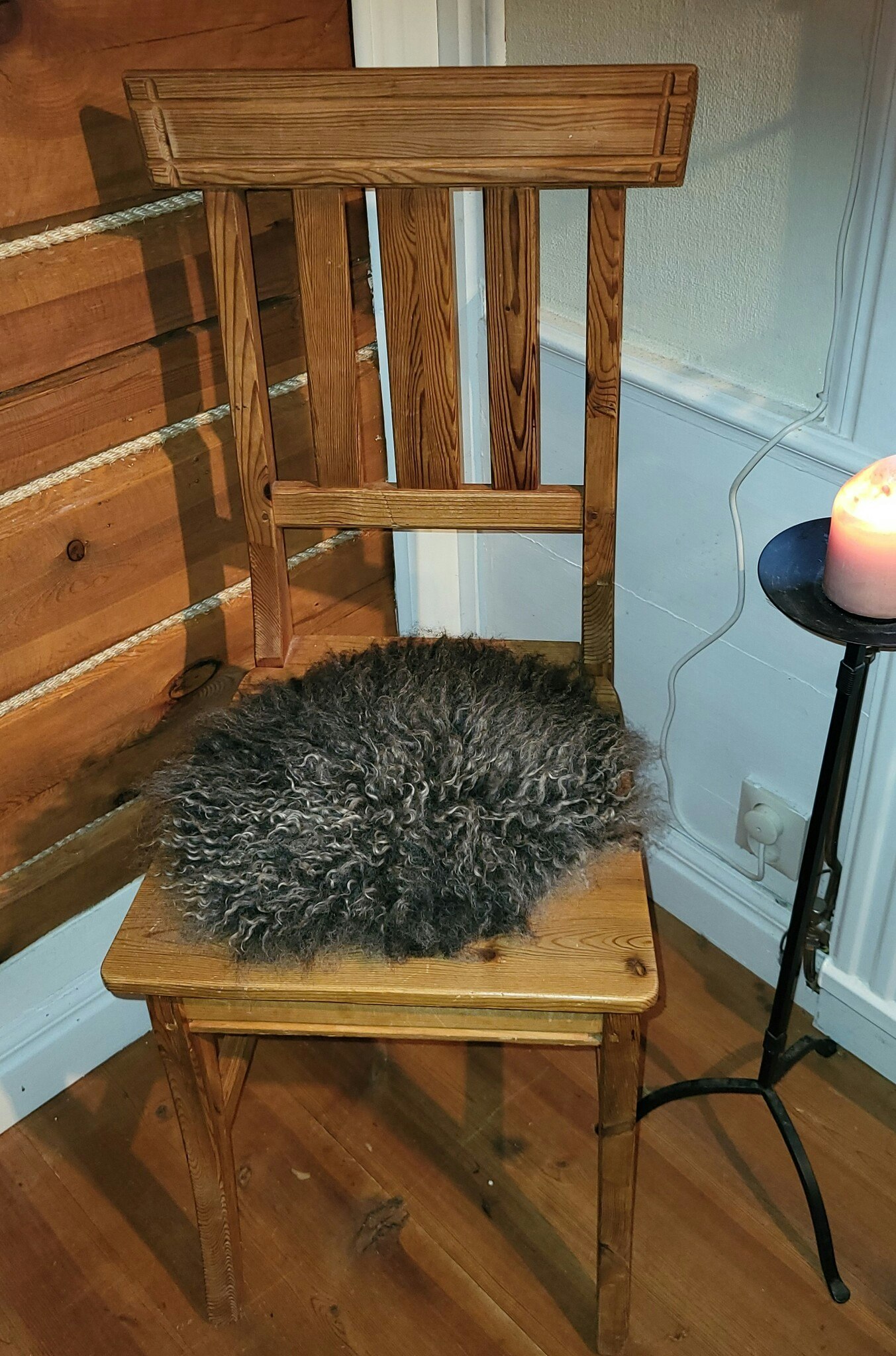 Stolsdyna av fårskinn, svart med silvergrå lockar.