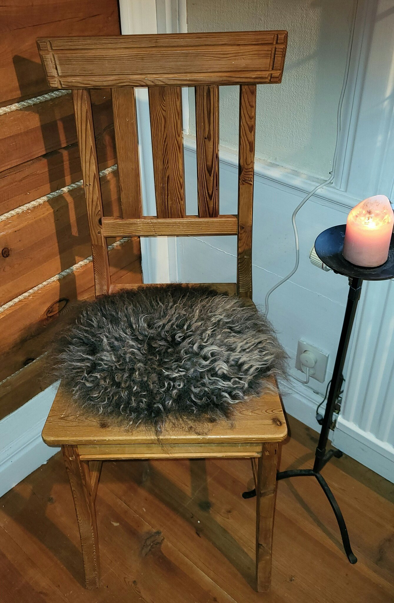 Stolsdyna av fårskinn, svart med silvergrå lockar.