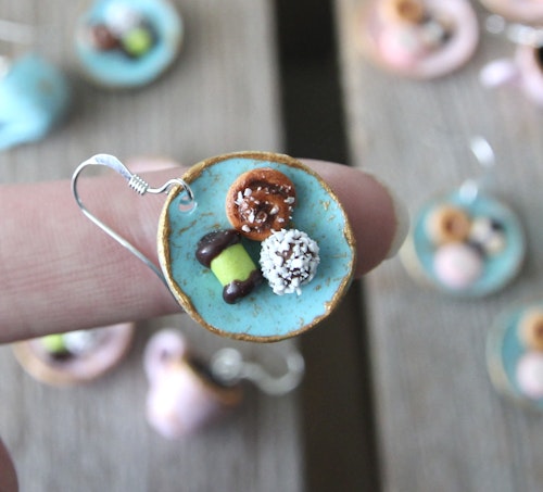 Örhängen, blåa fikatallrikar med dammsugare, chokladboll och kanelbulle
