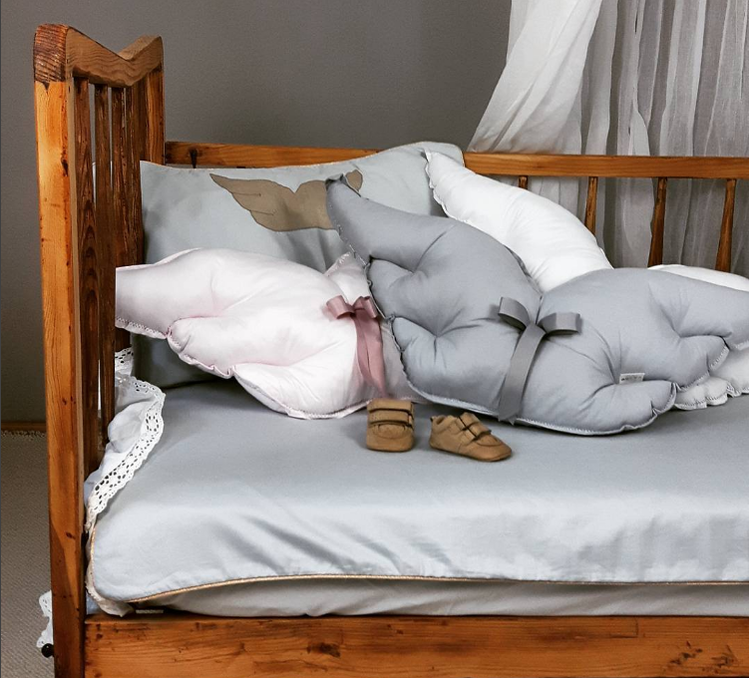 Puderrosa kudde vingar grå och vit vingarkuddar på en säng