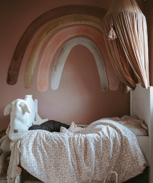 Babylove, dusty pink rainbow, regnbåge väggklistermärke Väggklistermärken uppsatta på en vägg ovanför en säng