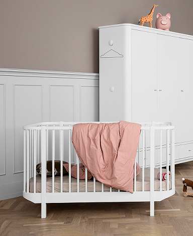 Oliver Furniture, spjälsäng vit Vit spjälsäng med ett täcke i ett barnrum