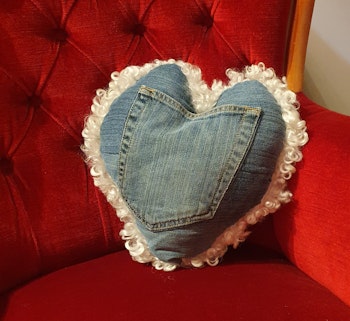 Vit hjärtformad fårskinnskudde med återbrukat jeanstyg