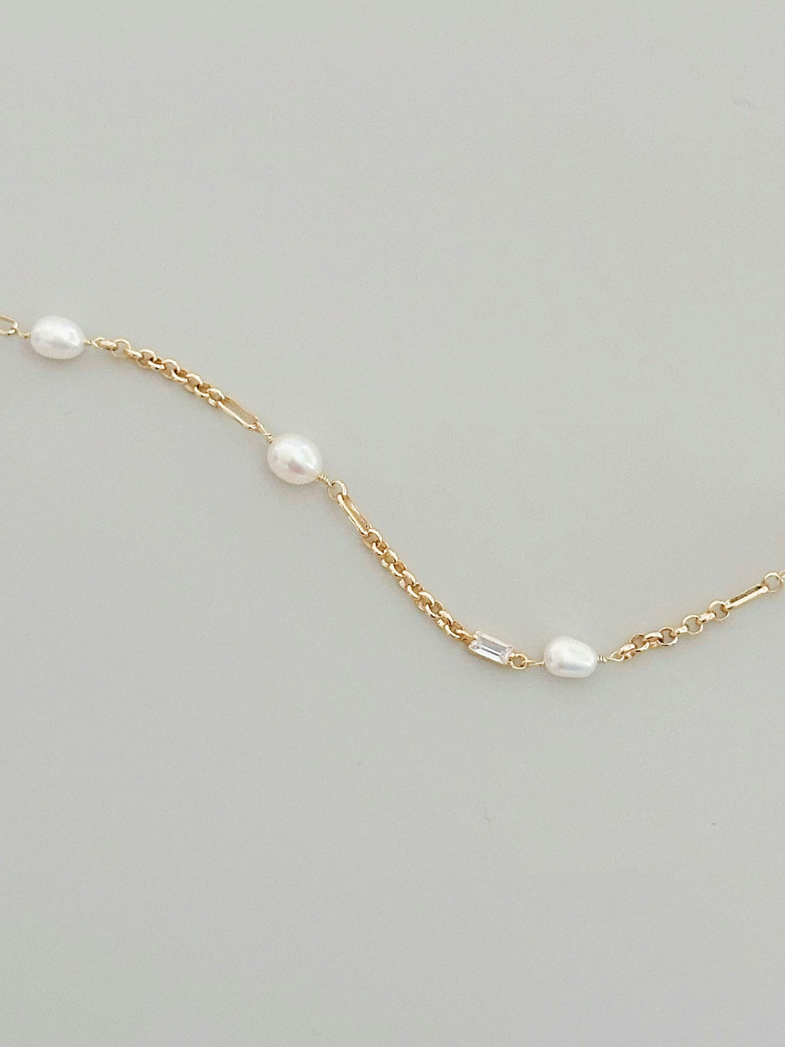 Tunt guldfärgat halsband med ovala vita pärlor