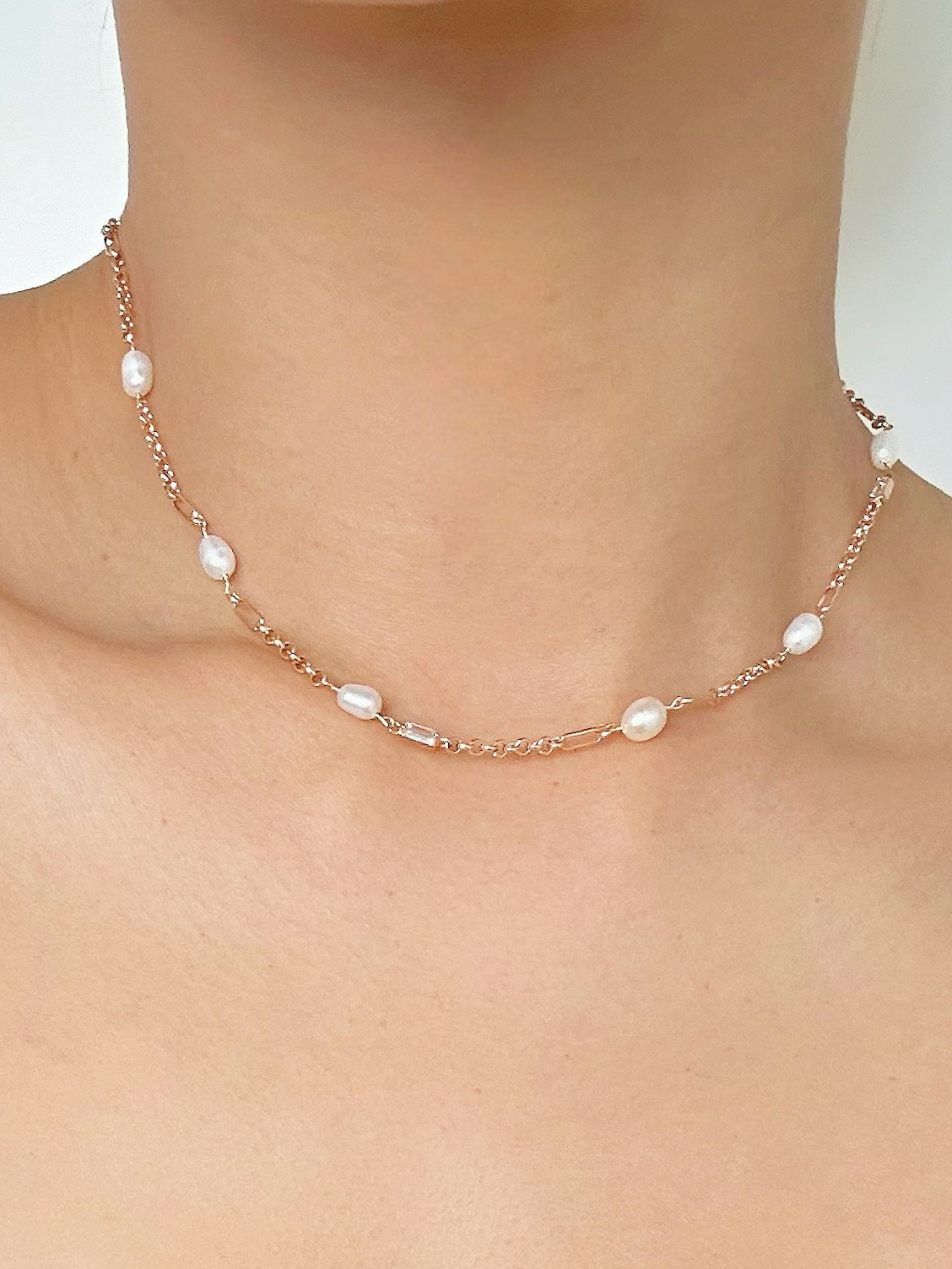 Tunt guldfärgat halsband med ovala vita pärlor