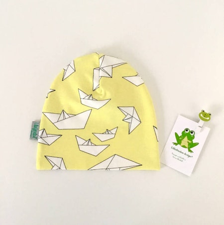 Mössa med tecknade pappersbåtar i origami, gul