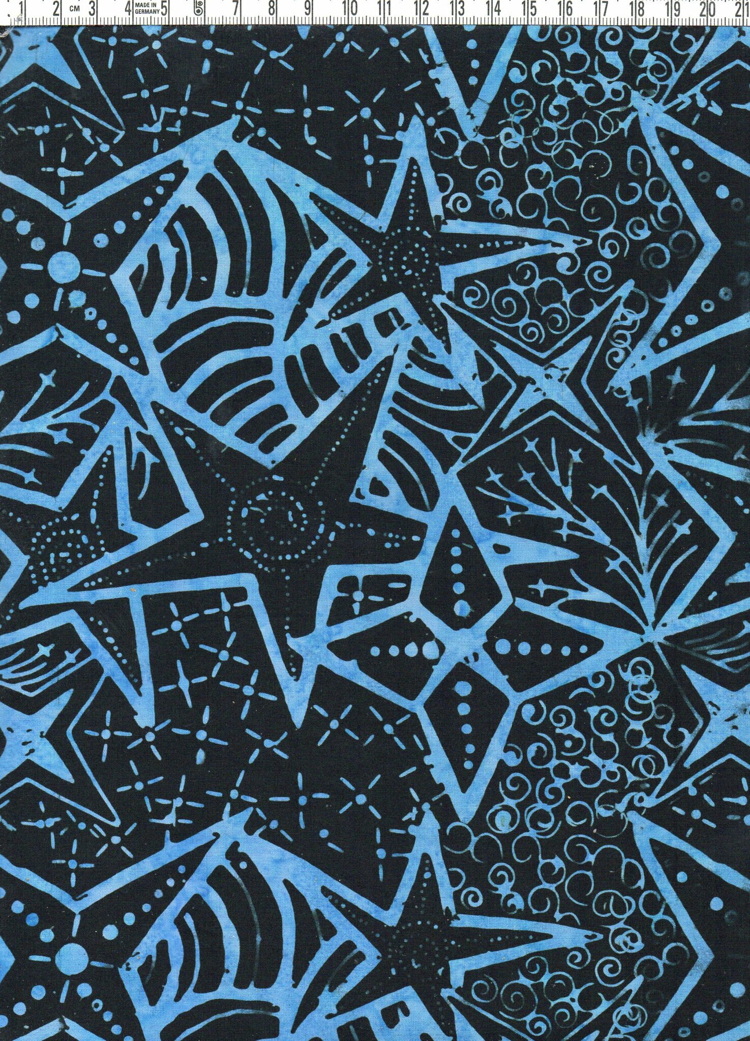Superdesignade stjärnor i blåaste blått på svart himmel. Batik bomull. Ca 110 cm brett.