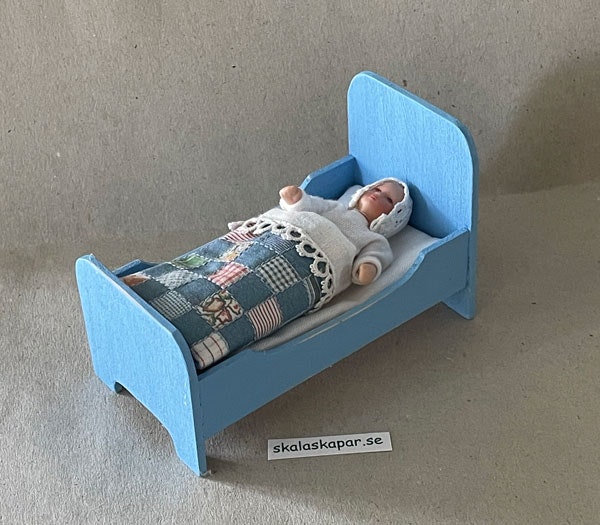 Liten blå säng med lapptäcke