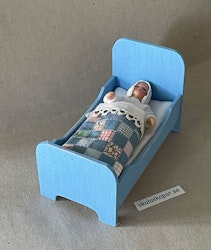 Liten blå säng med lapptäcke