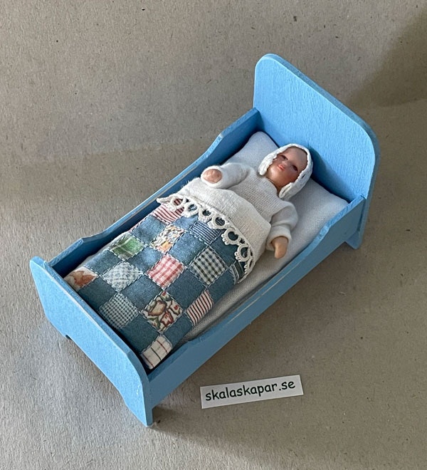 Liten blå säng med lapptäcke