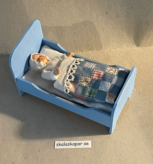 Liten blå säng med lapptäcke
