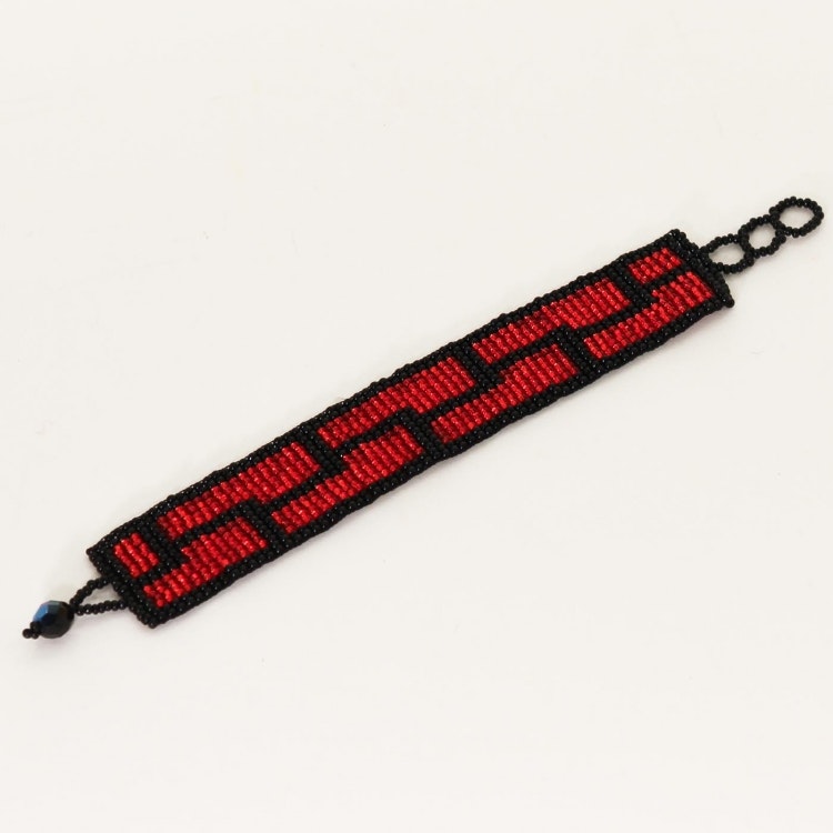 Smycke: armband av mycket små glaspärlor i röd & svart. Mönstret påminner om en vacker tegelstensmur i två rader.