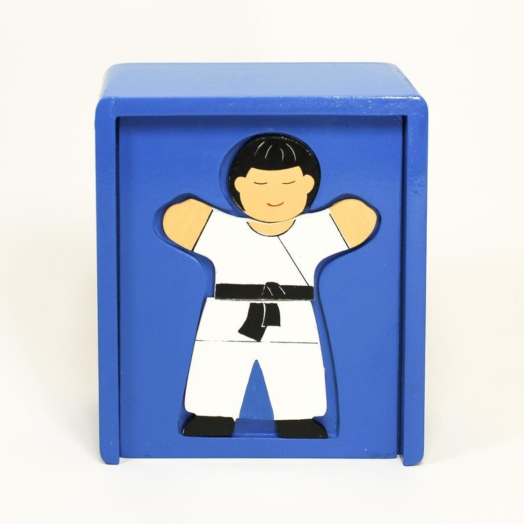 Sluten blå låda med schablon för pussel-läggande. En färdig pusselbild, syns: barn i judoklädsel, Japan.