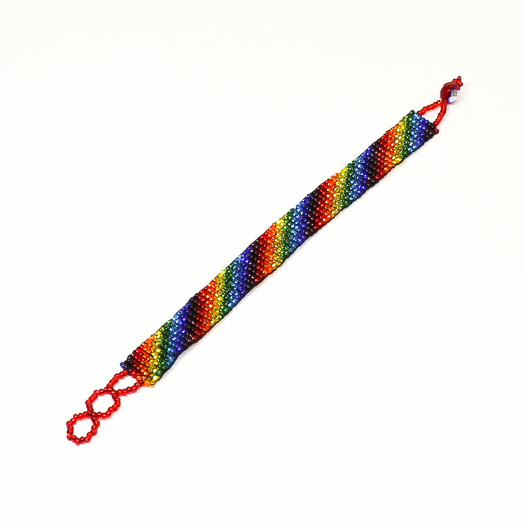 Armband i regnbågsfärger, sammansatt av mycket små glaspärlor, oknäppt. Fair Trade från Guatemala.