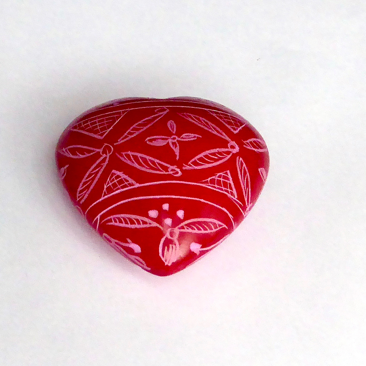 Dekorativt litet rött hjärta med vackert mönster. Ett en hjärtevän. Handgjort av täljsten i Kenya för Fair Trade.