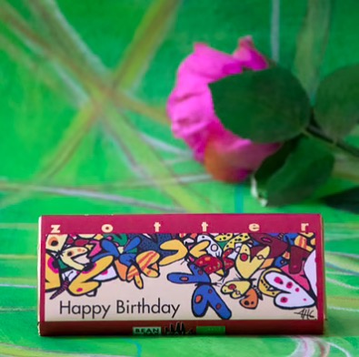 Zotter Happy birthday, exklusiv mjölkchokladkaka, karamellkräm och mandelnougat. Fair Trade & ekologisk. Bild med dekoration.