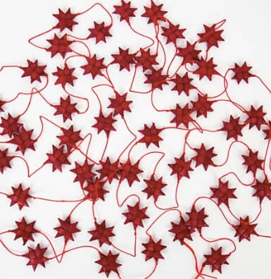 Små vikta röda stjärnor som girlang, 450 cm. Handgjorda av palmblad på bomullssnöre. Fair Trade från Bangladesh  för Afroart.