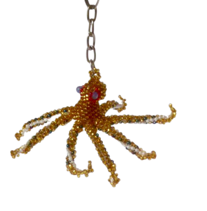 Nyckelring i form av en åttaarmad bläckfisk, oktopus, pärlad för hand av små glaspärlor av mayakvinnor i Guatemala. Gyllen färg på ovansidan.