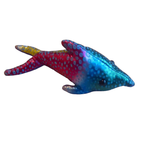 Sanddjur, liten delfin i glittrigt blått, grönt gult och rött mönster. Fylld med kvartssand. Fair Trade.