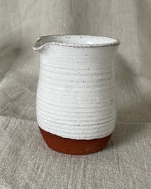 Liten vit kanna i rödbrun lera