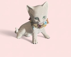 Porslins katt som sitter med blommor runt halsen*