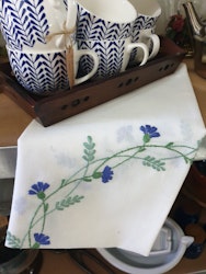 Vit duk med broderade blå blommor och grönt