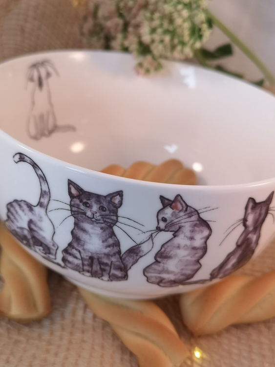 Fyra katter tillsammans med möss syns på denna sida av skålen samt en vit katt på insidan.
