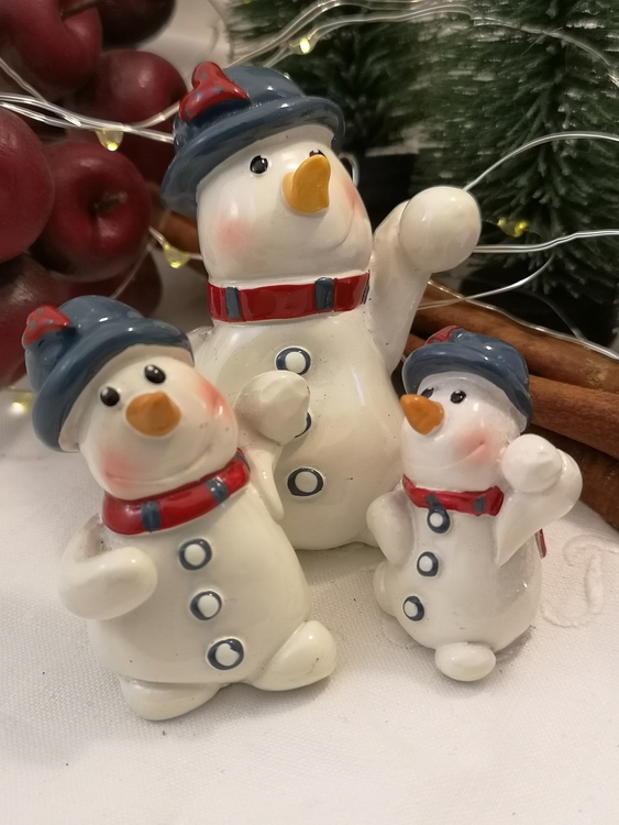 Tre figurer i olika storlekar föreställande snögubbar med halsduk och hatt med snöboll i ena handen.