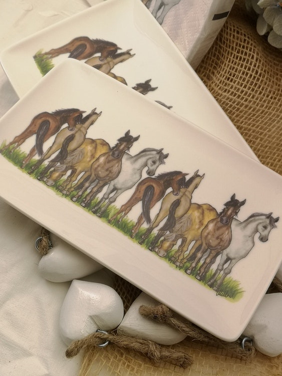 Hästassiett i porslin med rektangulär form med hästar på rad. Hästarna har olika färger och står på gräs.