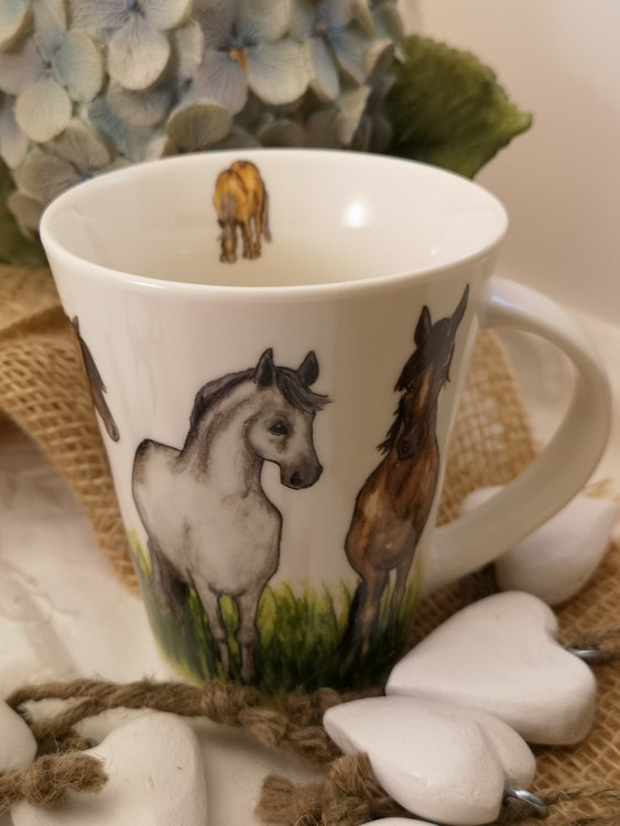 Motiv med hästar och högt gräs på mugg. Ytterligare mindre häst på insidan av koppen.