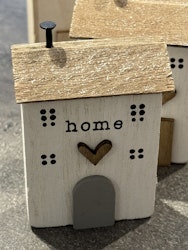 Litet hus i trä med text "Home"