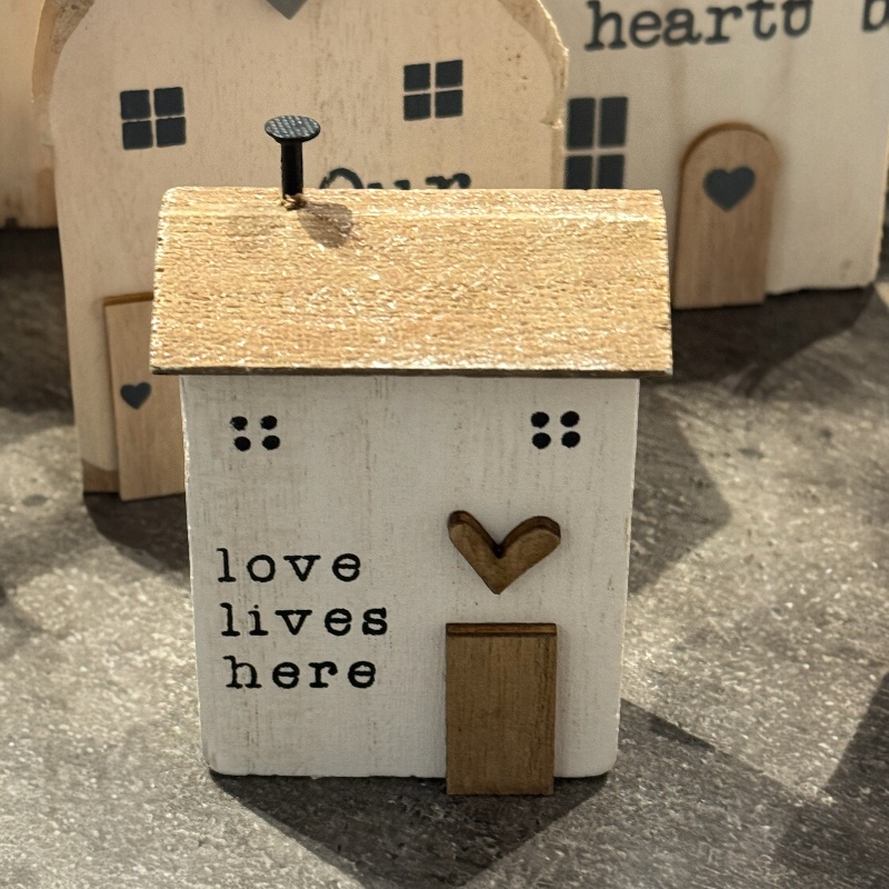 Litet hus i trä med text "Love..."