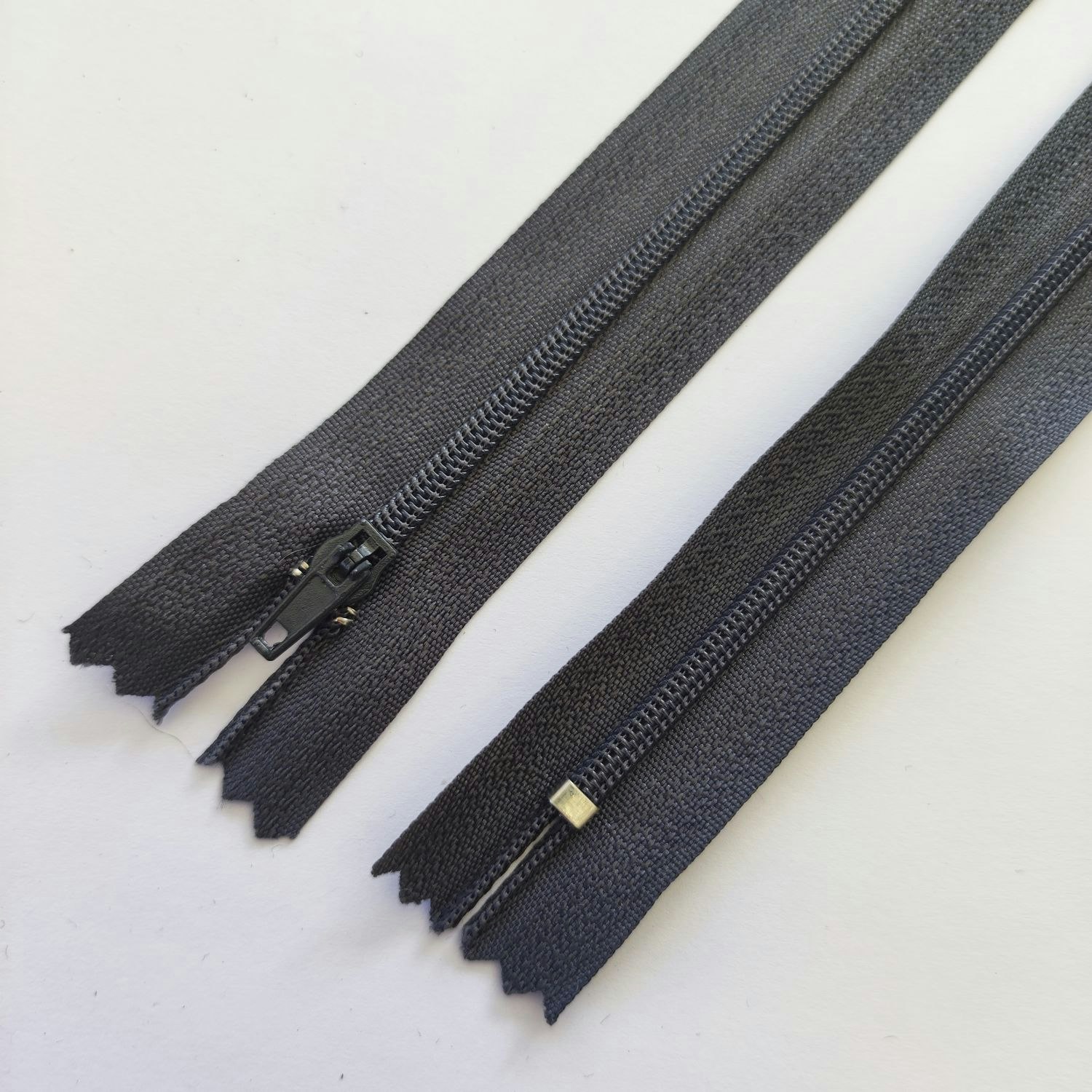 18 cm dragkedja. Mörkgrå.