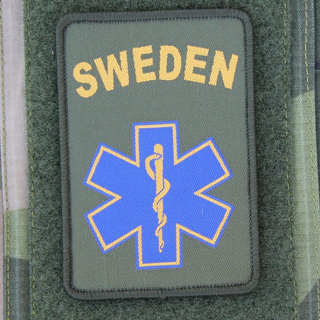 SWE MEDIC Star Hook Patch mounted on arm of a M90 camouflage jacket.