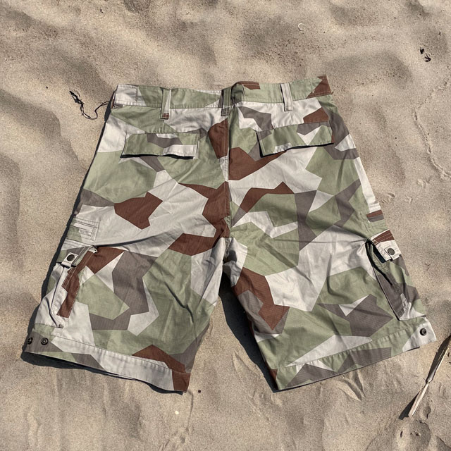 A pair of Camp Shorts M90K Desert from TAC-UP GEAR  lying flat on the sand seen from the back