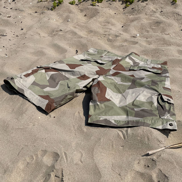 A pair of Camp Shorts M90K Desert from TAC-UP GEAR  lying flat on the sand seen from the back